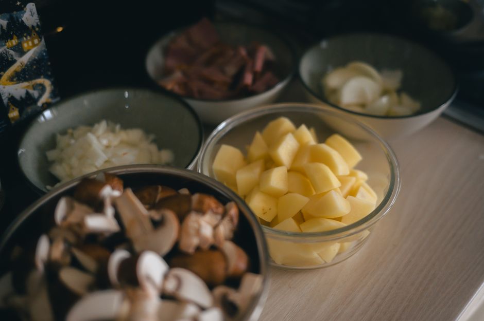 Various chopped vegetables and meats arranged in bowls for cooking preparation.